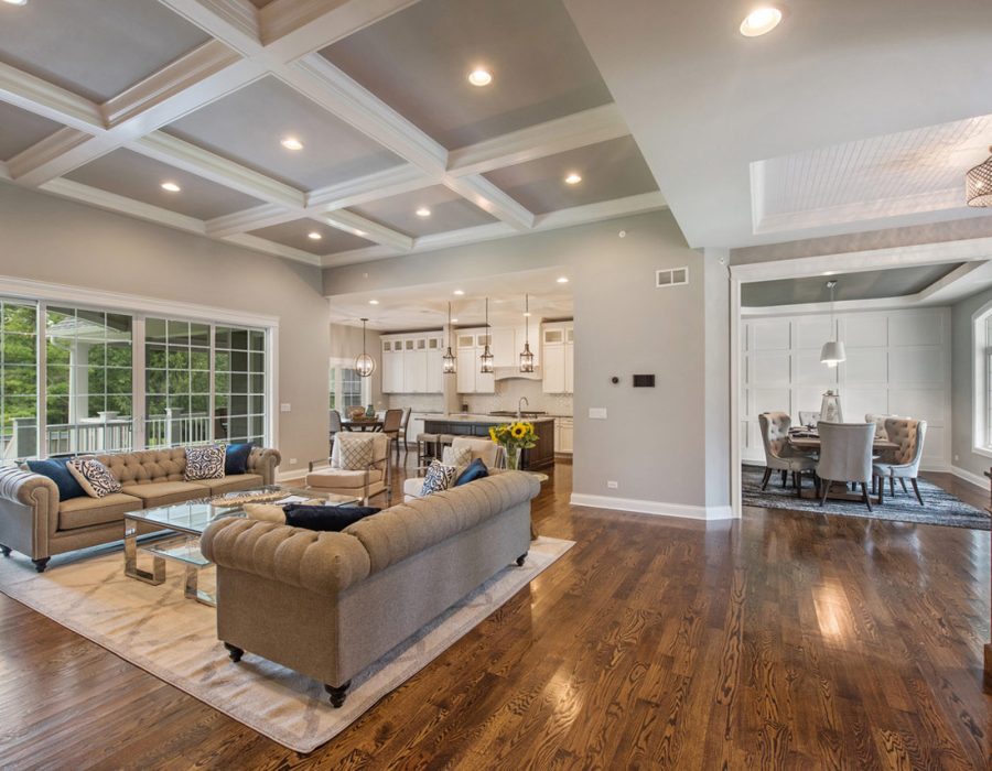 Spacious and elegant living room seamlessly integrated with a dining area, featuring luxurious sofas, large windows, and a sophisticated neutral color palette.