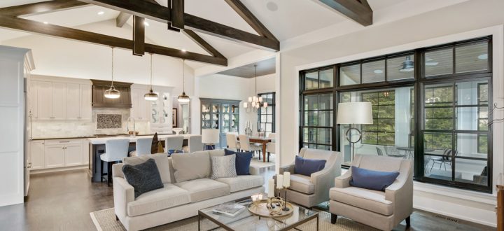 An elegant interior view of a luxury home with high ceilings supported by dark wooden beams, blending modern and traditional decor elements in a neutral color palette.